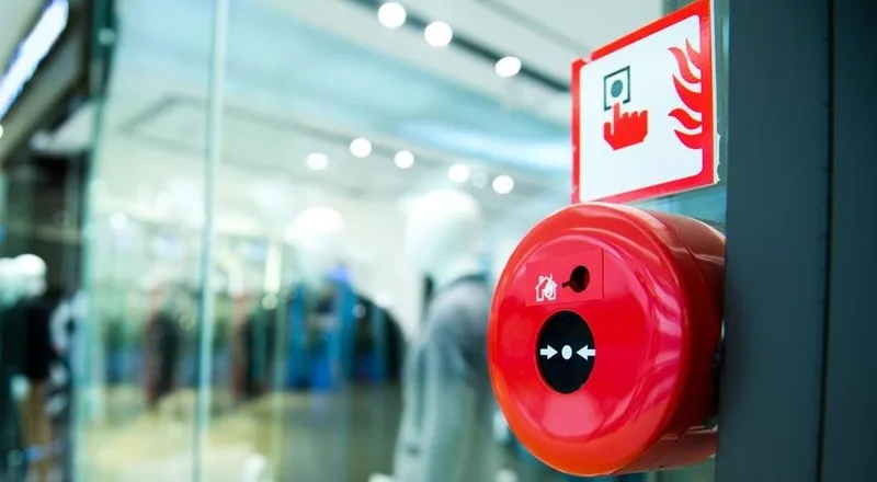A red manual call point on a shopping centre wall